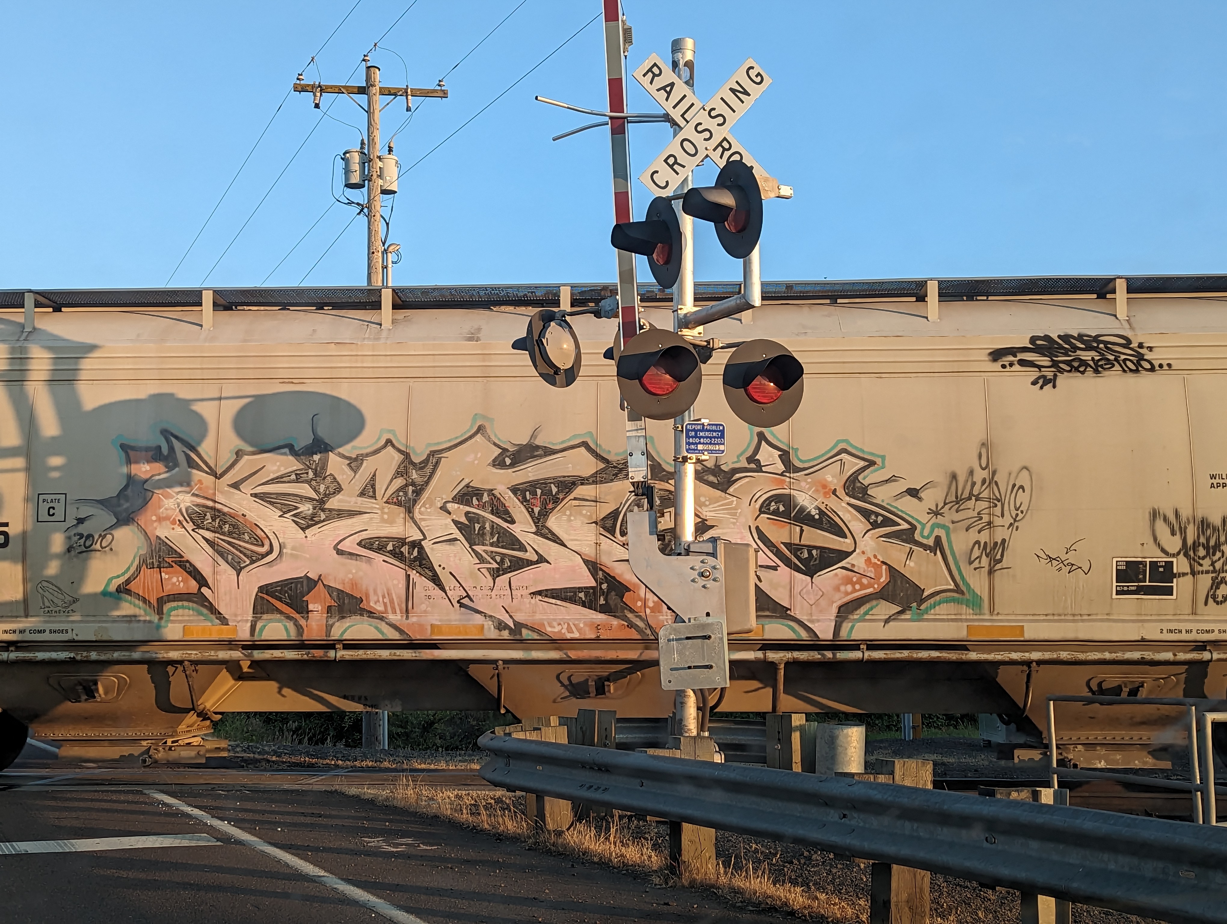 A
        train car with graffiti going through a railroad crossing